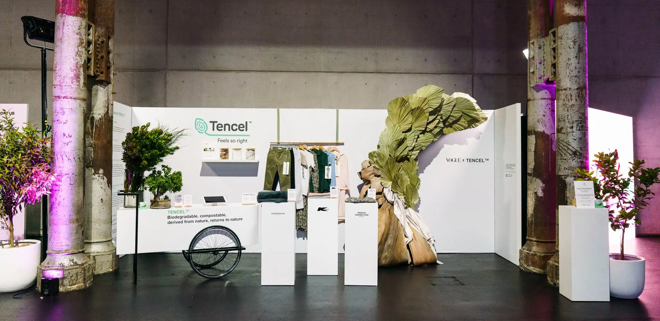 Vogue x Tencel showcase booth with sustainable clothing display and palm frond installation